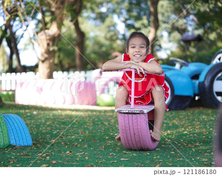 Cute girl playing in the playground during summer vacation. Happy children having fun in an outdoor park. Cute girl playing in the playground during summer vacation. Happy children having fun in an outdoor park. 121186180