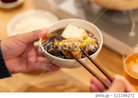 冬の夜のリビングで夕食の鍋料理を楽しむ男性の手元 121186272