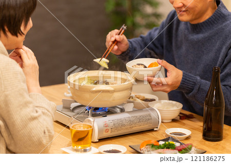冬の夜のリビングで夕食の鍋料理を楽しむミドル夫婦 冬の夜のリビングで夕食の鍋料理を楽しむミドル夫婦 121186275