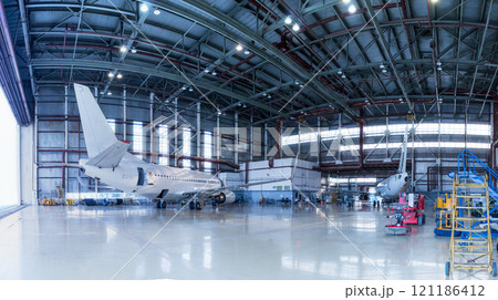 Passenger aircrafts under maintenance. Checking mechanical systems for flight operations. Panorama of airplanes in the hangar 121186412