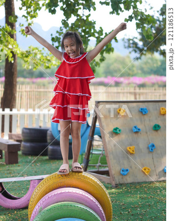 Cute girl playing in the playground during summer vacation. Happy children having fun in an outdoor park. Cute girl playing in the playground during summer vacation. Happy children having fun in an outdoor park. 121186513