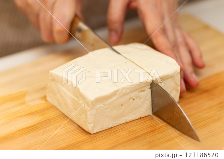 まな板で木綿豆腐を切るミドル女性の手元 121186520