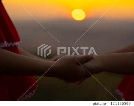 Two little girls holding hands on a summer sunset background. Family love with colorful sunset. 121186599