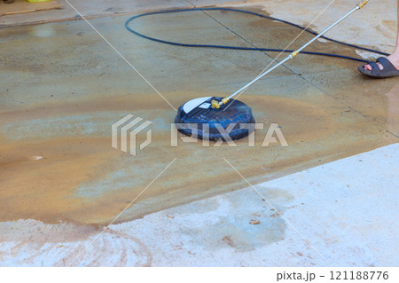 Water sprays onto concrete surface as pressure washer is used for cleaning, showing effective outdoor maintenance. Water sprays onto concrete surface as pressure washer is used for cleaning, showing effective outdoor maintenance. 121188776
