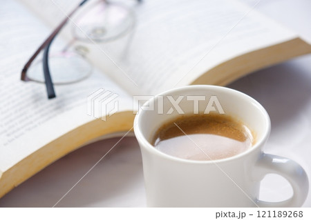 ページを開いた本(洋書)とコーヒーの入ったコーヒーカップで、コーヒーを飲みながら読書を楽しむイメージ ページを開いた本(洋書)とコーヒーの入ったコーヒーカップで、コーヒーを飲みながら読書を楽しむイメージ 121189268