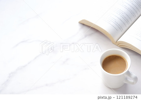 ページを開いた本（洋書）とコーヒーの入ったコーヒーカップで、コーヒーを飲みながら読書を楽しむイメージ 121189274