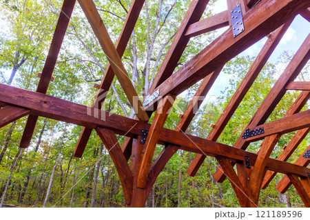Wooden framework gazebo rises among green trees under clear blue sky, during construction built gazebo Wooden framework gazebo rises among green trees under clear blue sky, during construction built gazebo 121189596