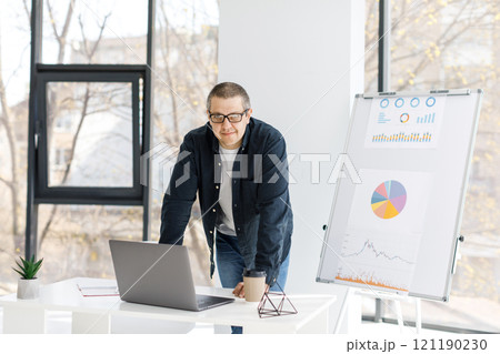 A man, strong physique, dressed in casual clothes works in the office 121190230