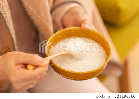 お粥（白がゆ）を食べる女性の手元 121190360