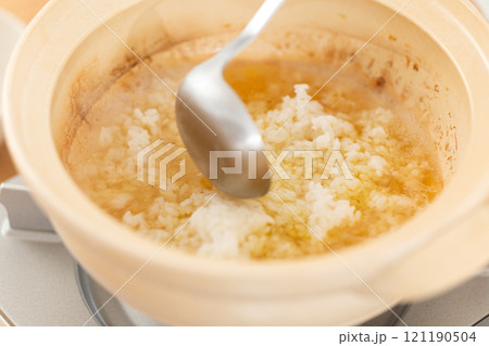 鶏鍋の残り汁でおじや(雑炊)を作る男性の手元 鶏鍋の残り汁でおじや(雑炊)を作る男性の手元 121190504