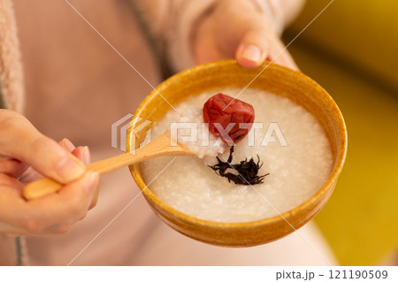 梅干しの乗ったお粥（梅がゆ）を食べる女性の手元 121190509
