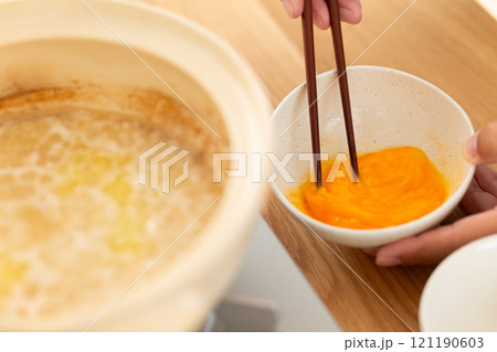 鶏鍋の残り汁でおじや（雑炊）を作る男性の手元 121190603