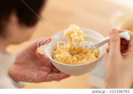 鍋の締めにおじや（雑炊）を作って食べるミドル女性 121190781
