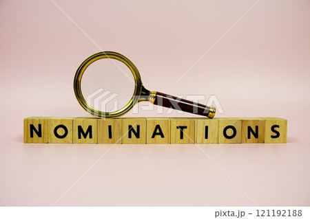 Magnifying glass and paper card with text NOMINATIONS on pink background Magnifying glass and paper card with text NOMINATIONS on pink background 121192188