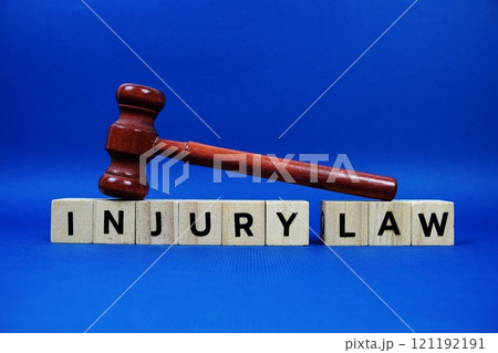 Injury Law alphabet letters with wooden blocks alphabet letters and Gavel on blue background 121192191
