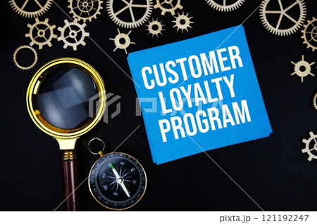 Customer Loyalty Program text message on sticky note with magnifying glass and compass on black background 121192247