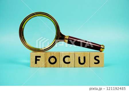 Focus with wooden blocks alphabet letters and Magnifying glass on blue background 121192485