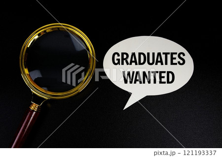 Graduates wanted text on speech bubble with magnifying glass top view on black background 121193337