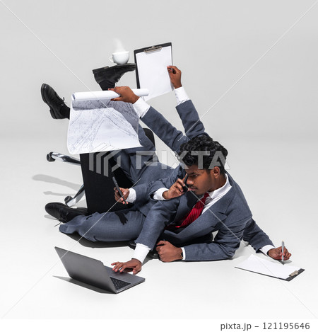 Relentless multitasking demands of corporate life. Businessman in suit balances various office tools, including documents, phone, and laptop 121195646