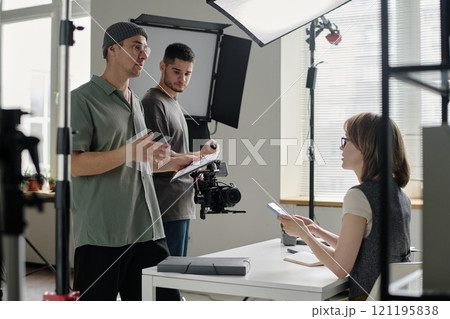 Male talented director discussing shooting day with crew, actress looking at him and listening his speech while cameraman setting device 121195838