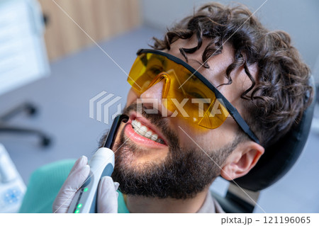 Man in protective glasses in dentist chair having teeth care procedures Man in protective glasses in dentist chair having teeth care procedures 121196065