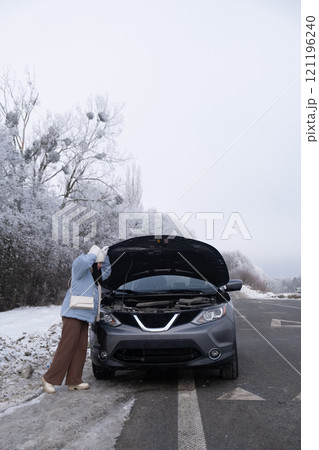 Woman watching at Car Engine on Snowy Roadside Woman watching at Car Engine on Snowy Roadside 121196240