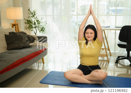 Calm and focused young woman meditating during a yoga session at home 121196982
