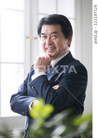 腕を組むシニアの経営者や社長などの 笑顔でカメラ目線のポシティブイメージ 腕を組むシニアの経営者や社長などの 笑顔でカメラ目線のポシティブイメージ 121197126