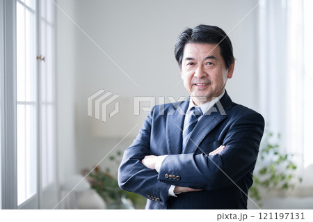 腕を組むシニアの経営者や社長などの 笑顔でカメラ目線のポシティブイメージ 121197131