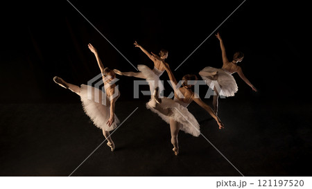 Lightness and weightlessness. Graceful and elegant ballerinas in white tutus in motion, creating striking visual, dancing on dark stage 121197520