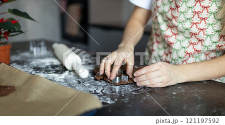 Raw dough, cookie cutters and rolling pin on table. Mother in apron making gingerbread biscuits with cookie cutters. Winter holidays concept, web banner, no face. Merry Christmas and Happy Holidays. 121197592