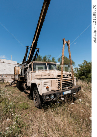 Vintage Construction Crane Truck Rusting in Overgrown Field 121199370