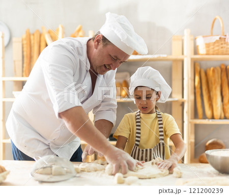 Father and daughter roll out dough together to make delicious bread Father and daughter roll out dough together to make delicious bread 121200239