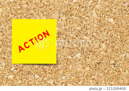Yellow note paper with word action on cork board background with copy space 121200408
