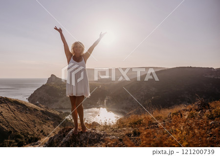 woman standing hill with her arms raised in the air, looking up at the sun. The scene is peaceful and serene, with the woman's expression conveying a sense of joy and happiness. woman standing hill with her arms raised in the air, looking up at the sun. The scene is peaceful and serene, with the woman's expression conveying a sense of joy and happiness. 121200739