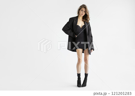 Beautiful young brunette woman In Oversized Black Blazer, mini dress and Boots Standing isolated on white background. Full Body Fashion model posing in studio, beauty, elegance and modern style 121201283