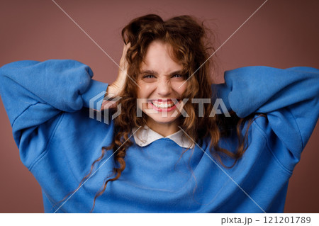 Happy surprised young adult woman wearing winter blue sweater and hold head with her hands looking at camera with joyful smile Happy surprised young adult woman wearing winter blue sweater and hold head with her hands looking at camera with joyful smile 121201789