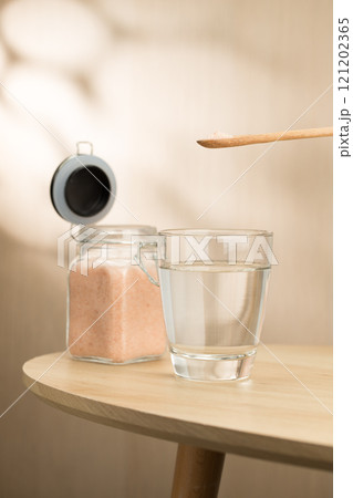 A spoon of Himalayan salt is being added to a glass of drinking water. A spoon of Himalayan salt is being added to a glass of drinking water. 121202365