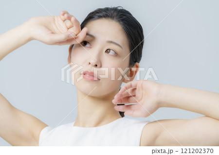 グレー背景の白いワンピースを着る若い女性のポートレート 121202370