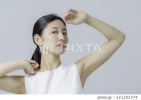 グレー背景の白いワンピースを着る若い女性のポートレート 121202374