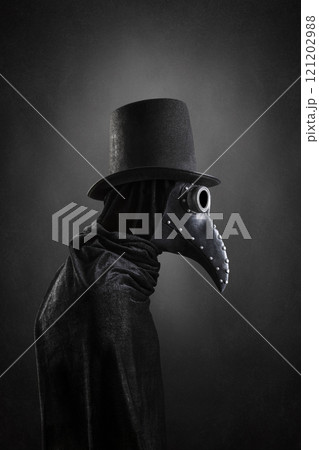 Plague doctor with black vintage top hat at night over dark misty background  121202988