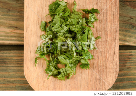 Top view of chopped fresh coriander leaves on wooden cutting board. 121202992