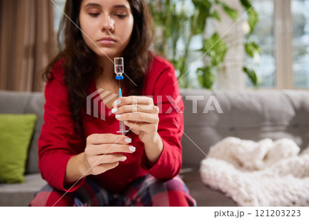 Young girl prepares drug for injection, removes air from syringe in order to painlessly give herself injection. 121203223