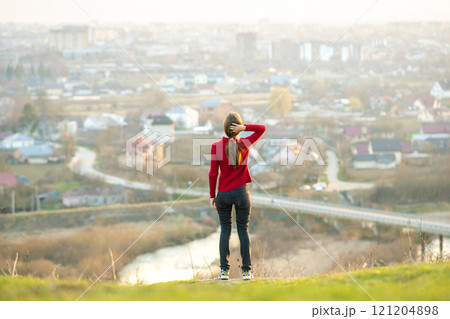 Young woman standing outdoors enjoying city view. Relaxing, freedom and wellness concept. 121204898