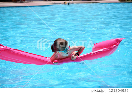 Young child girl falling in water from inflatable air mattress in swimming pool while swinnimg during tropical vacations. Safety of aquatic activities concept Young child girl falling in water from inflatable air mattress in swimming pool while swinnimg during tropical vacations. Safety of aquatic activities concept 121204923
