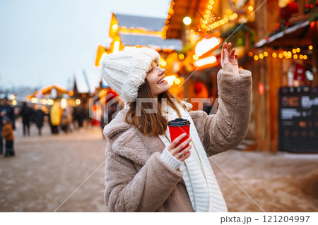Woman with coffee in winter over outdoor ice skating rink on background. Winter holidays concept. 121204997