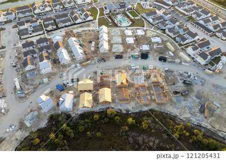 Unfinished frames of inexpensive homes with wooden roof beams under construction. Development of residential housing in US suburbs. Real estate market in the USA 121205431
