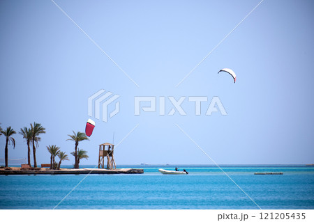 Tropical sea pier with palms and recreational zone, tourists windsurfing and kite surfing. Summer exotic vacations 121205435