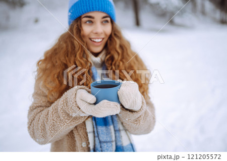 Smiling woman with a thermos in a snowy forest enjoying nature. Adventure concept. Lifestyle. 121205572