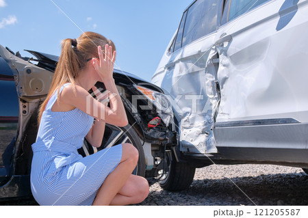 Sad female driver sitting on street side shocked after car accident. Road safety and vehicle insurance concept 121205587